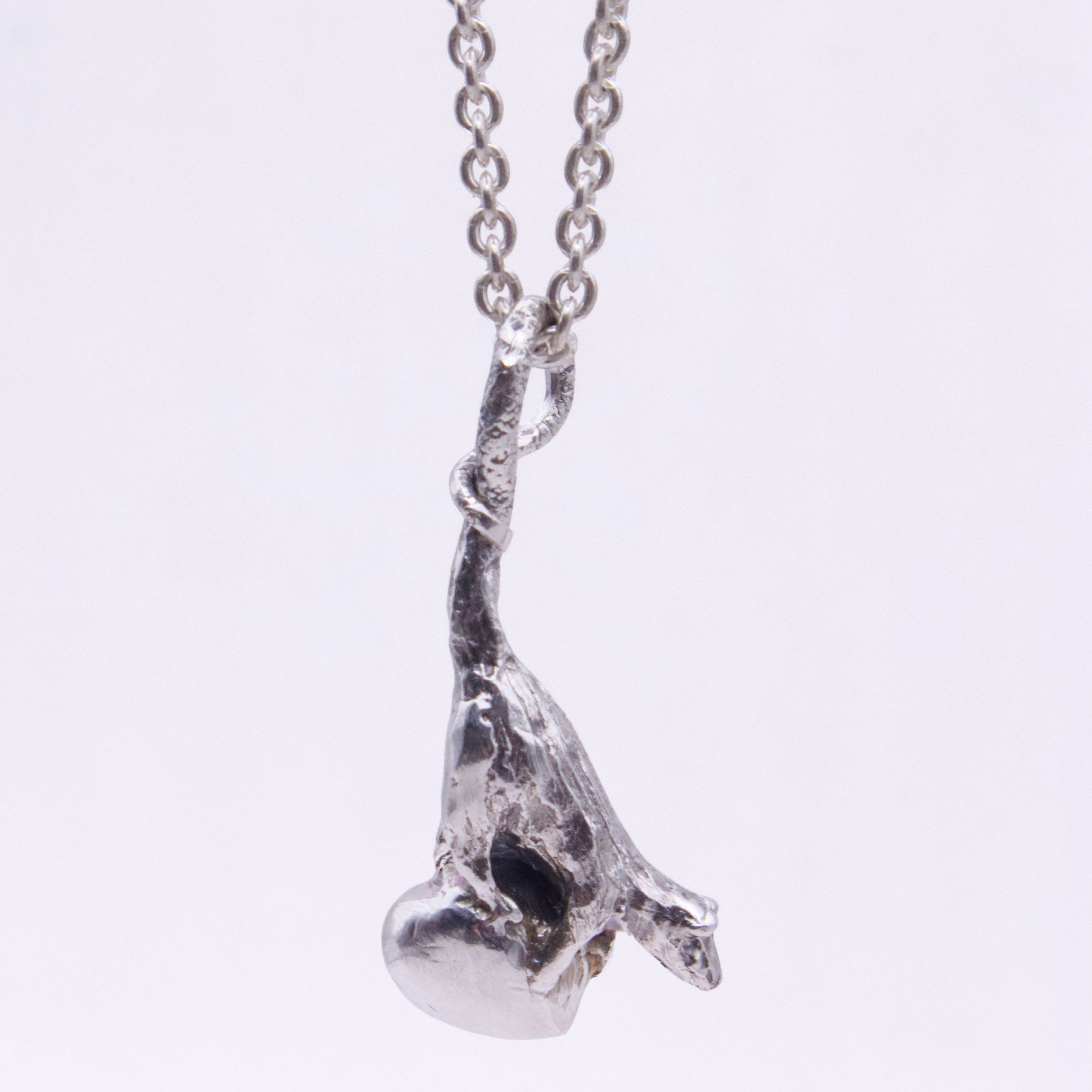 A silver pendant necklace featuring a textured, organic rat-shaped charm hanging from a silver link chain, shown against a plain white background.