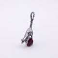 A silver pendant shaped like a leaping rat holding a dark red gemstone, shown on a plain white background.