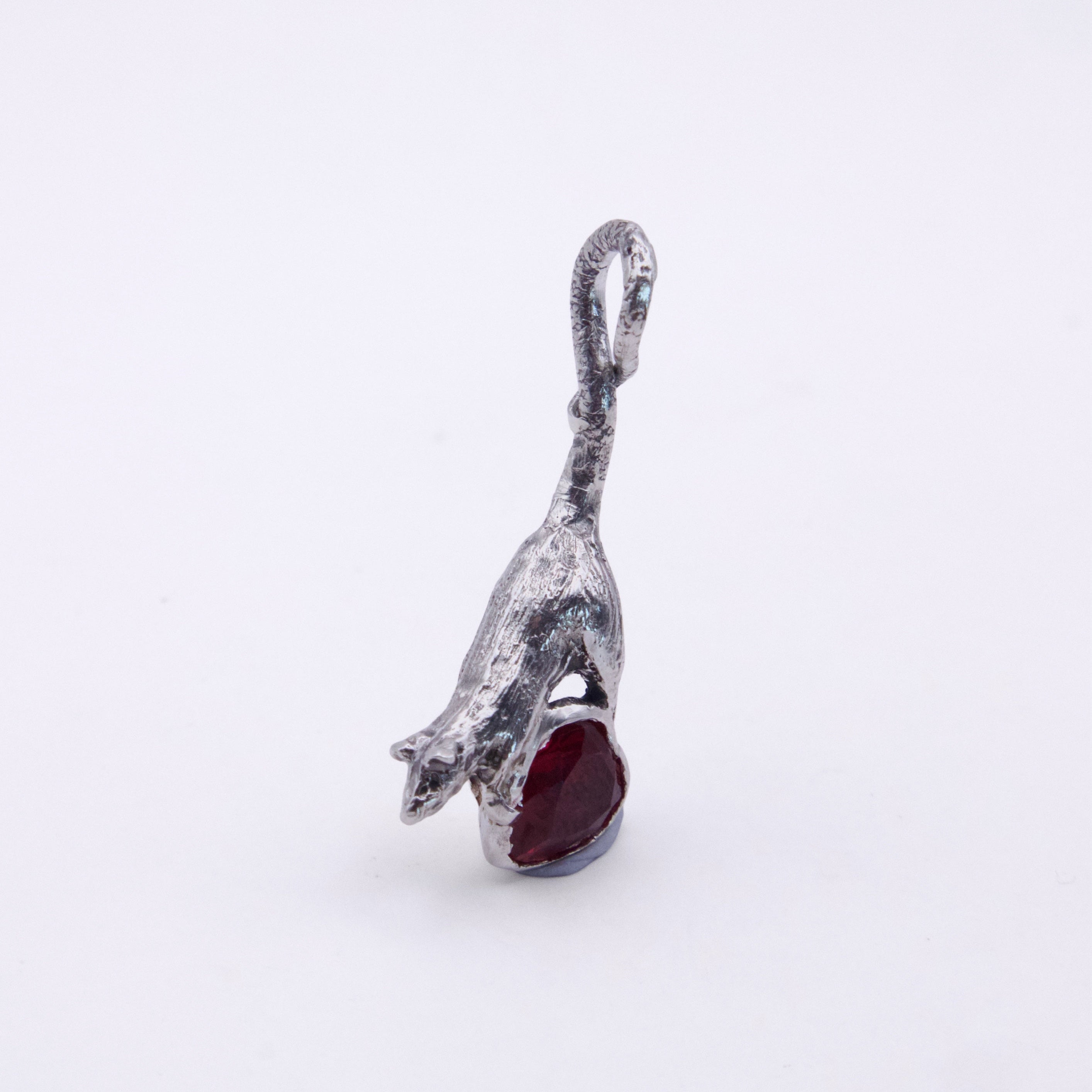 A silver pendant shaped like a leaping rat holding a dark red gemstone, shown on a plain white background.