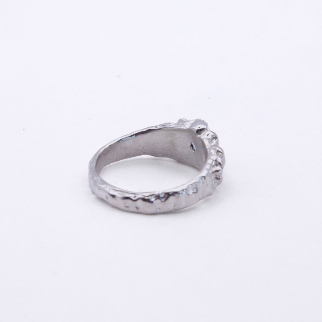 A textured silver ring with a hammered finish and a small decorative protruding detail on the front, shown on a plain white background.