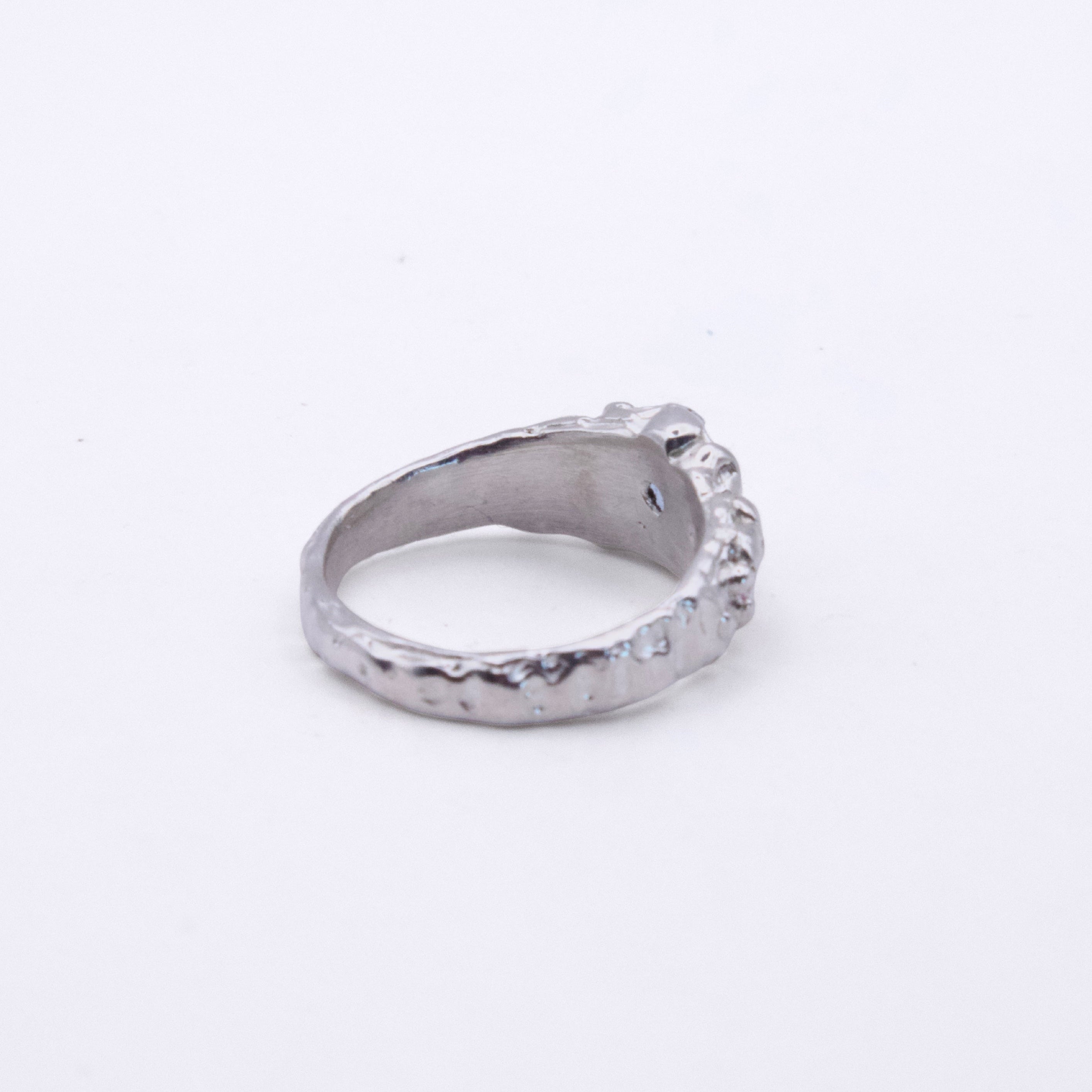 A textured silver ring with a hammered finish and a small decorative protruding detail on the front, shown on a plain white background.