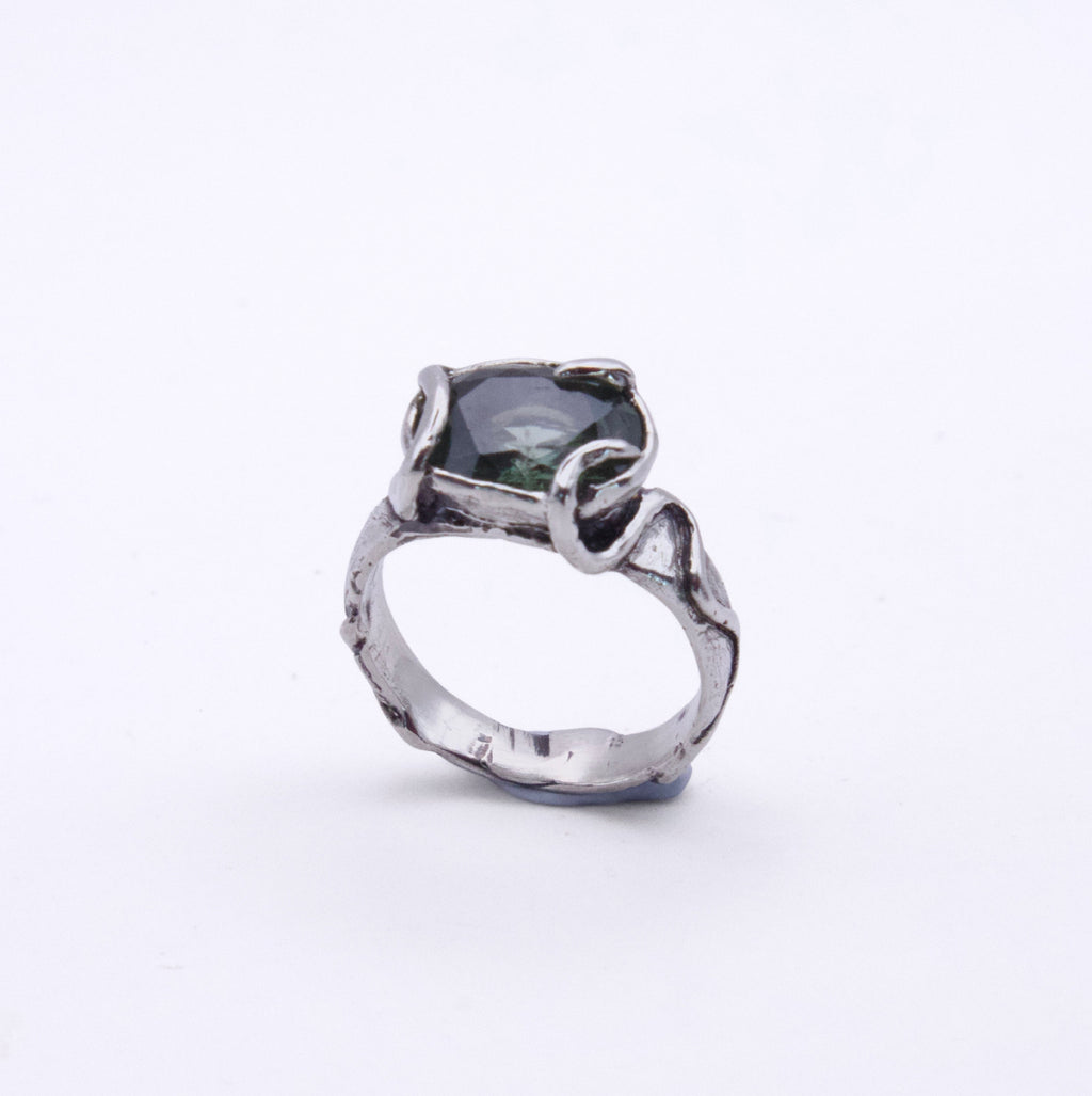 A silver ring with a textured, organic-shaped band and a dark green rectangular gemstone, shown on a plain white background.