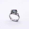 A silver ring with a textured, organic-shaped band and a dark green rectangular gemstone, shown on a plain white background.