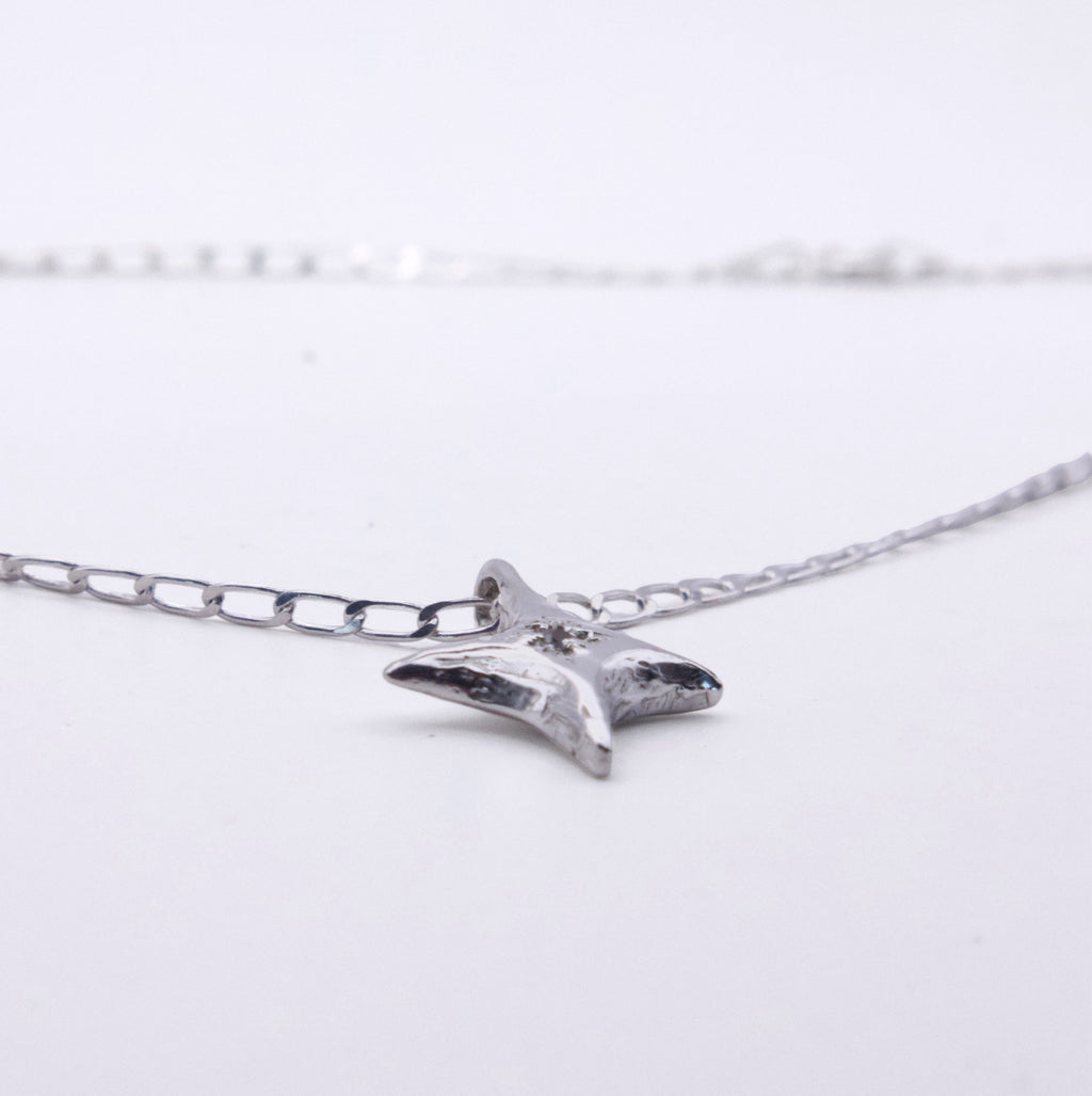 A silver starfish pendant necklace on a delicate silver chain, photographed against a clean white background.