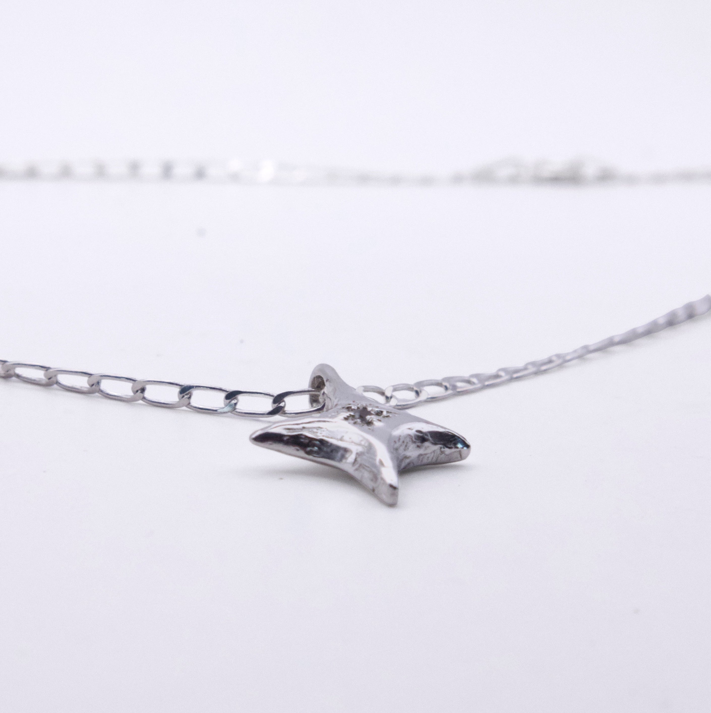 A silver starfish pendant necklace on a delicate silver chain, photographed against a clean white background.