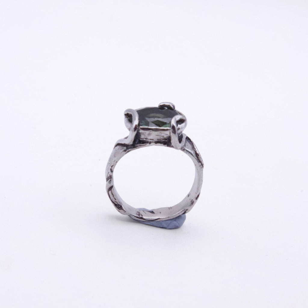 A silver-toned ring with a textured, hammered band and a central dark green rectangular gemstone, shown on a plain white background.