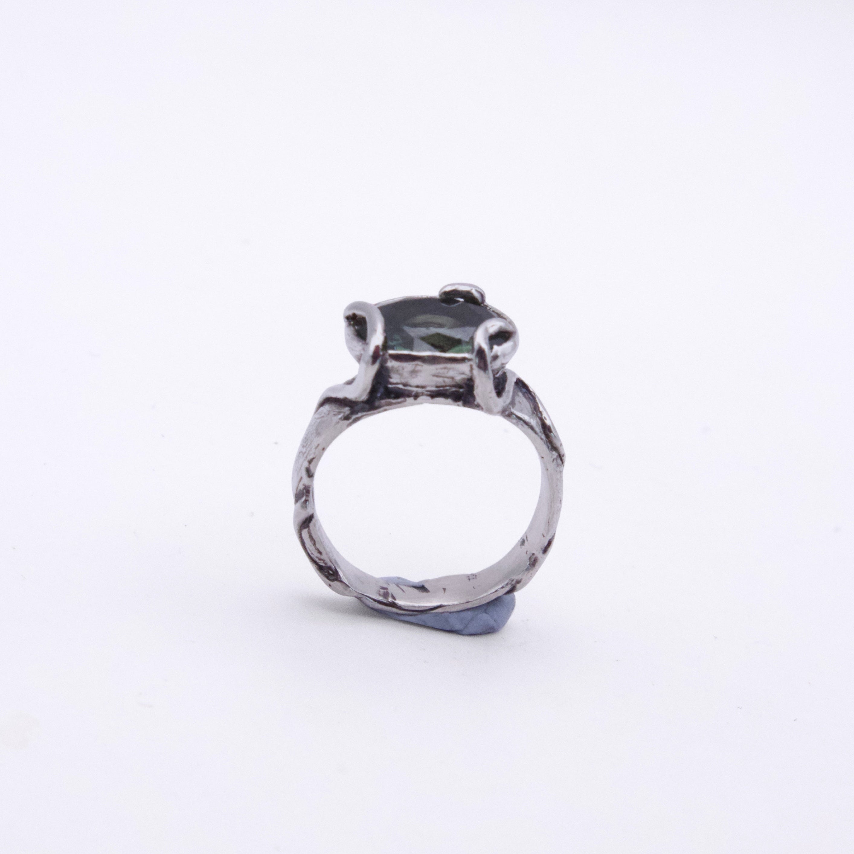 A silver-toned ring with a textured, hammered band and a central dark green rectangular gemstone, shown on a plain white background.